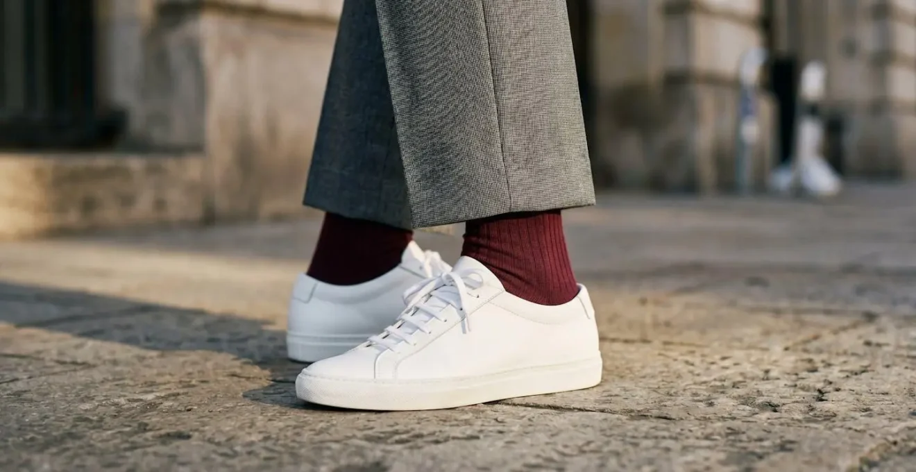 Dettaglio gambe con pantaloni sartoriali, calzini a coste e sneakers bianche