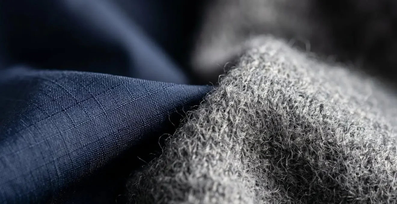 Dettaglio ravvicinato di tessuti tecnici e cashmere sovrapposti che mostrano un contrasto di texture.