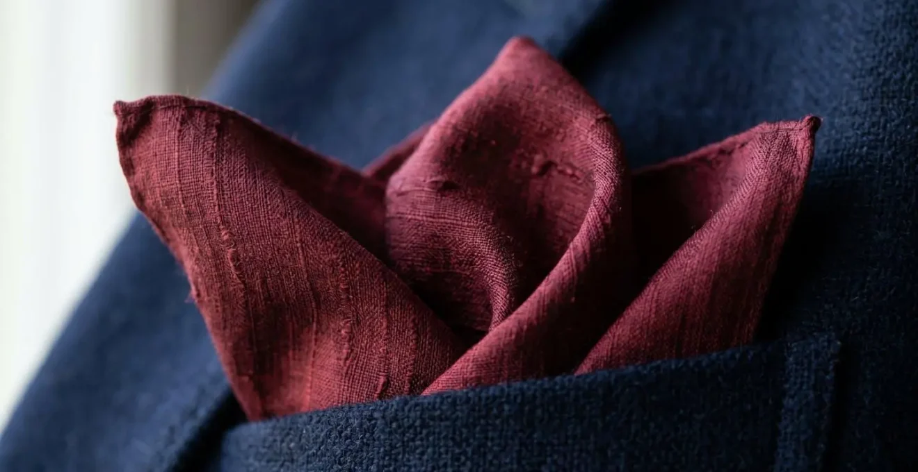 Dettaglio macro di una pochette di seta nel taschino di una giacca con piega a sbuffo naturale