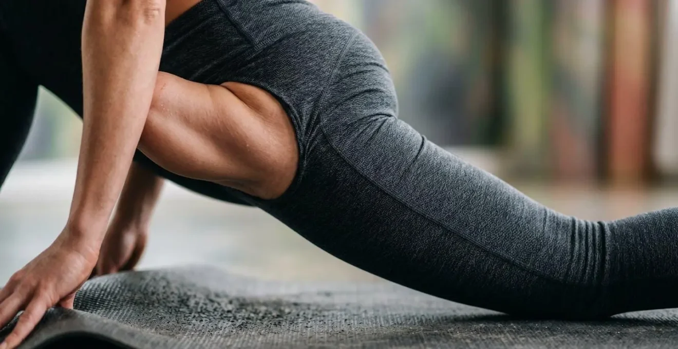 Uomo che esegue una variante della posizione della lucertola su tappetino, con focus sulla tensione muscolare dell'anca.