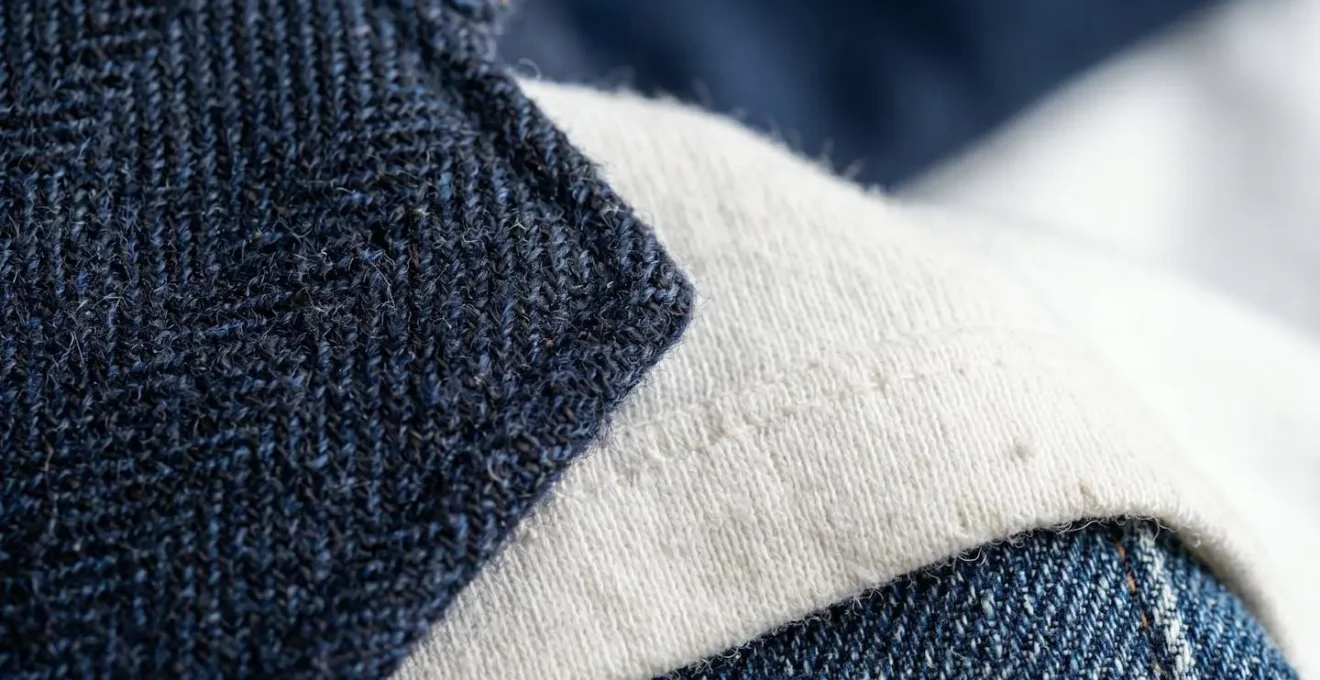 Composizione macro di tessuti sovrapposti che mostra la texture di blazer sopra maglietta e jeans